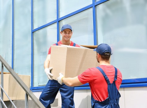 Movers carrying furniture on a residential street in Anerley